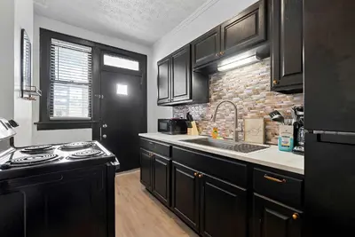 a kitchen with black cabinets and a sink and a stove at Merion Village Residences 1166 in Columbus
