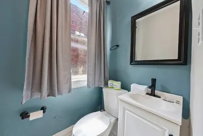 a bathroom with a toilet and a sink and a mirror at Merion Village Residences Suites in Columbus