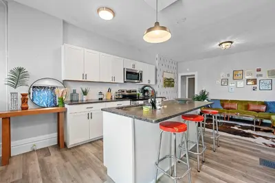a kitchen with white cabinets and red bar stools at Merion Village Residences Suites in Columbus