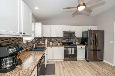 a kitchen with white cabinets and stainless steel appliances at Poolside Paradise Near the Ark in Walton