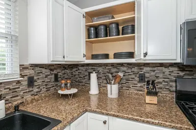 a kitchen counter with white cabinets and a sink at Poolside Paradise Near the Ark in Walton
