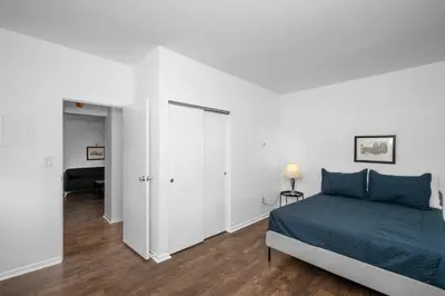 a white bedroom with a blue bed and a hallway at Northside Suites 1 - Best Retreat for Couples in Cincinnati