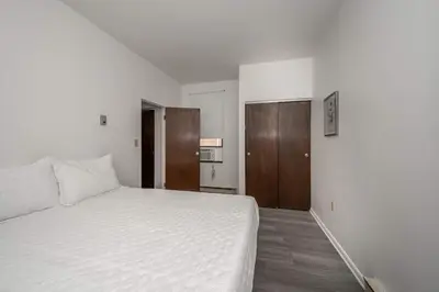 a bedroom with a white bed and wooden cabinets at Northside Suite 2 - Cozy Escape in Cincinnati