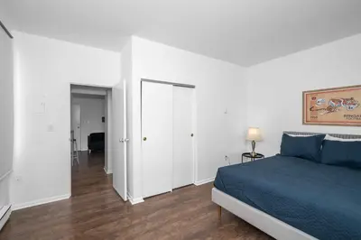 a white bedroom with a blue bed and a hallway at Northside Suites 3 - A Chic Relaxed Stay for 2 in Cincinnati