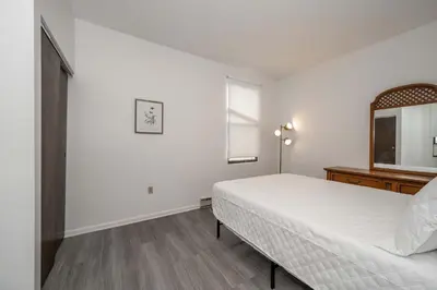 a white bedroom with a bed and a mirror at Northside Suites - 4 Apartments in Cincinnati