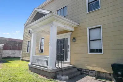 a yellow house with a porch and a door at Northside Suites - 4 Apartments in Cincinnati