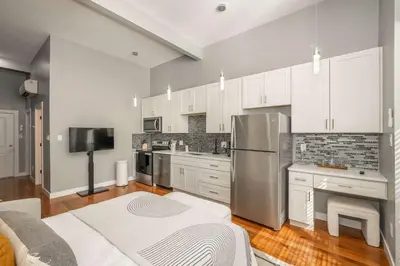 a kitchen with white cabinets and a stainless steel refrigerator at Findlay Market Suite 1 - For 2 in Cincinnati
