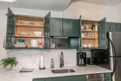 a kitchen with green cabinets and a sink at Mansfield Retreat - A Chic Downtown Experience in Cincinnati