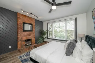 a bedroom with a bed and a brick fireplace at Mansfield Retreat - A Chic Downtown Experience in Cincinnati