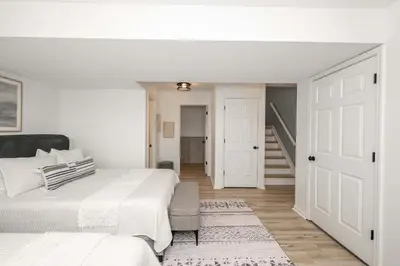 a white bedroom with two beds and a staircase at Walton Arkside Oasis in Walton