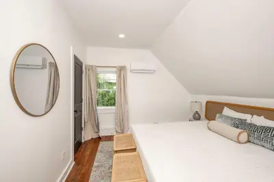 a white bedroom with a large bed and a mirror at Woodburn Villa by Blackhouse in Cincinnati