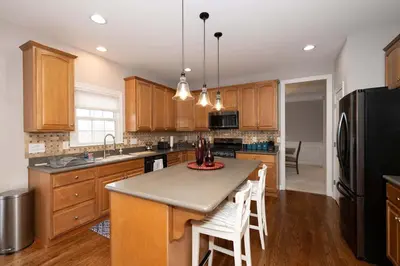 a kitchen with wooden cabinets and a black refrigerator at Mason Oasis 5 BDR Home Sweet Home Family-Friendly in Mason
