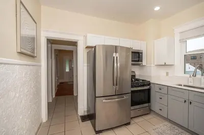a kitchen with a stainless steel refrigerator and white cabinets at The Cincinnati Cottage in Cincinnati