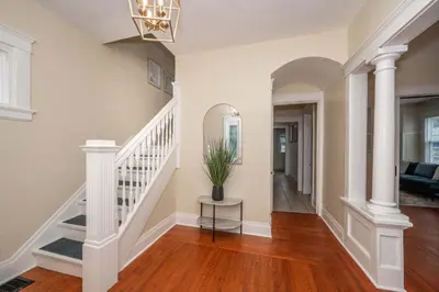 a hallway with white columns and a staircase with a potted plant at The Cincinnati Cottage in Cincinnati