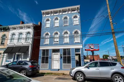 two cars parked in front of a blue building at Heart of Mainstrasse 1 in Covington