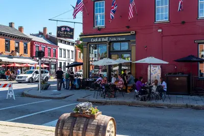 a city street with people sitting outside a restaurant at Heart of Mainstrasse 1 in Covington