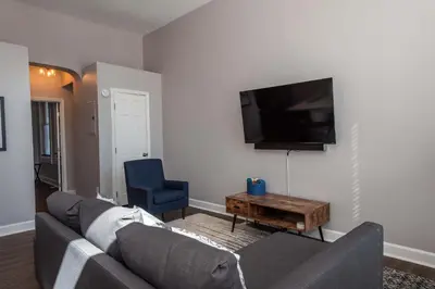 a living room with a couch and a tv on a wall at Heart of Mainstrasse 1 in Covington