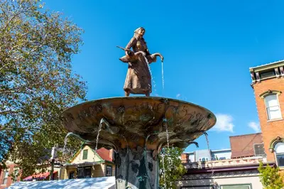 a statue of a woman standing on top of a fountain at Heart of Mainstrasse 2 in Covington