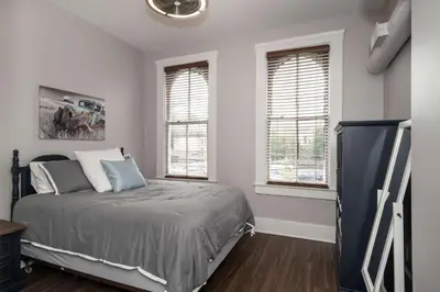 a bedroom with a bed and two windows at Heart of Mainstrasse 3 in Covington
