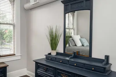 a black dresser with a mirror on top of it at Heart of Mainstrasse 3 in Covington