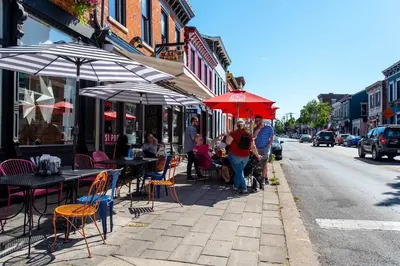 a group of people walking down a sidewalk with tables and umbrellas at Heart of Mainstrasse 4 in Covington