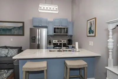 a kitchen with blue cabinets and a counter with stools at Heart of Mainstrasse Suites in Covington