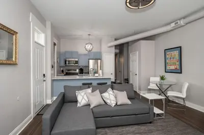 a living room with a gray couch and a kitchen at Heart of Mainstrasse Suites in Covington