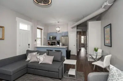 a living room with a gray couch and a kitchen at Heart of Mainstrasse Suites in Covington