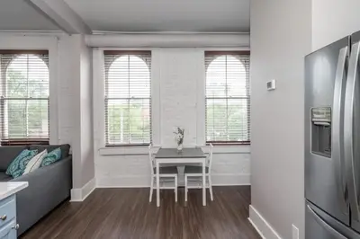a living room with a table and a kitchen with windows at Heart of Mainstrasse Suites in Covington