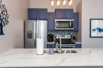 a kitchen with blue cabinets and a stainless steel refrigerator at Heart of Mainstrasse Suites in Covington
