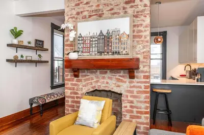 a living room with a brick fireplace with a yellow chair at Historic Retreat Gateway in Dayton