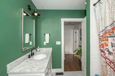 a bathroom with a sink and a green wall at Northside Nook Home for 6 in Cincinnati
