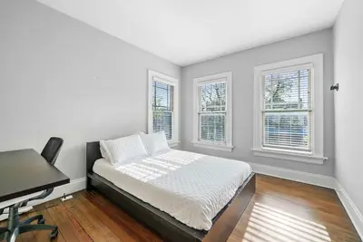 a bedroom with a bed and a desk and windows at Urban Elegance Getaway in Columbus