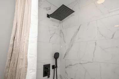 a shower with a white marble wall at LUXE Spot Suites in Covington