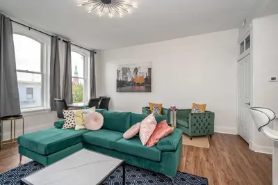a living room with a green couch and some windows at The Heart of Madison 3 in Covington