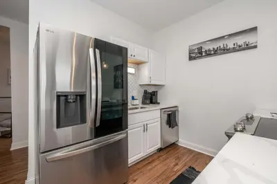 a kitchen with a stainless steel refrigerator and white cabinets at The Heart of Madison Suites in Covington