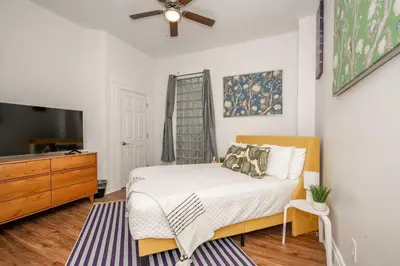 a bedroom with a bed and a flat screen tv at The Heart of Madison Suites in Covington