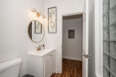 a white bathroom with a sink and a mirror at The Heart of Madison Suites in Covington
