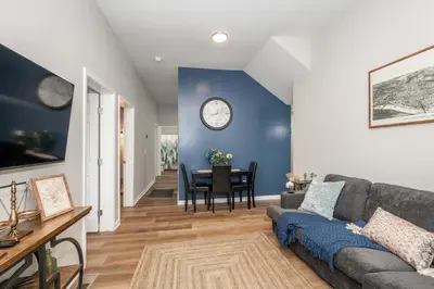 a living room with a couch and a clock on the wall at Queen City Retreat 1 Cozy Home for 6 Near Attractions & Restaurants in Cincinnati