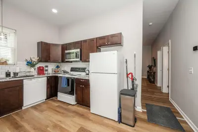 a kitchen with a white refrigerator and wooden cabinets at Queen City Retreat 1 Cozy Home for 6 Near Attractions & Restaurants in Cincinnati
