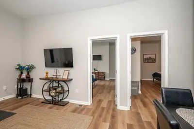 a living room with white walls and wooden floors at Queen City Retreat 1 Cozy Home for 6 Near Attractions & Restaurants in Cincinnati