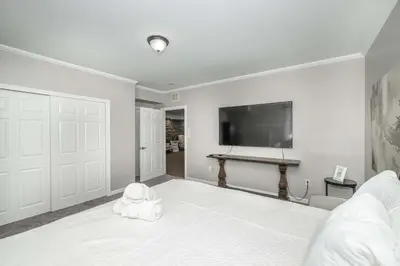 a bedroom with a white bed with a flat screen tv at The Bishops Manor Stay for 10 in West Chester
