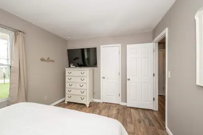 a bedroom with a white bed and a dresser at Main Street Cottage For 6 in Monroe