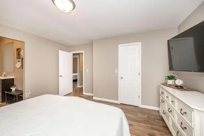 a bedroom with a white bed and a flat screen tv at Main Street Cottage For 6 in Monroe