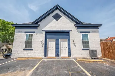 a white house with blue doors in a parking lot at Covington Charm 202 in Covington