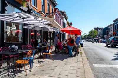a group of people walking down a sidewalk with tables and umbrellas at Covington Charm 201 in Covington