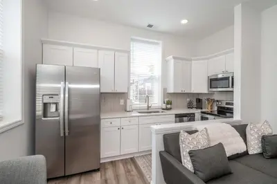 a kitchen with a stainless steel refrigerator and white cabinets at New Listing - Covington Charm Suites in Covington