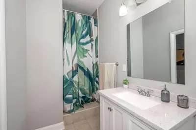 a bathroom with a sink and a shower with a mirror at Suites on Main 1 in Covington