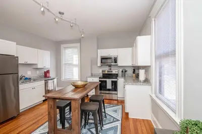 a kitchen with a wooden table and white cabinets at Suites on Main 2 in Covington