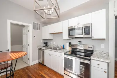 a kitchen with white cabinets and a sink and a table at Suites on Main 3 in Covington